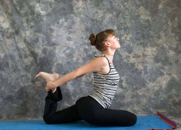 Genç kadın Yoga duruş kapotasana veya güvercin poz variati yapıyor — Stok fotoğraf