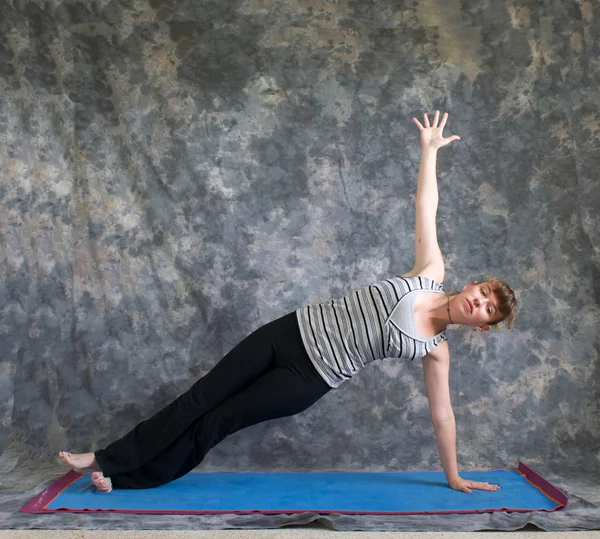 Jovem fazendo postura de Yoga Vasisthasana ou postura de prancha lateral — Fotografia de Stock
