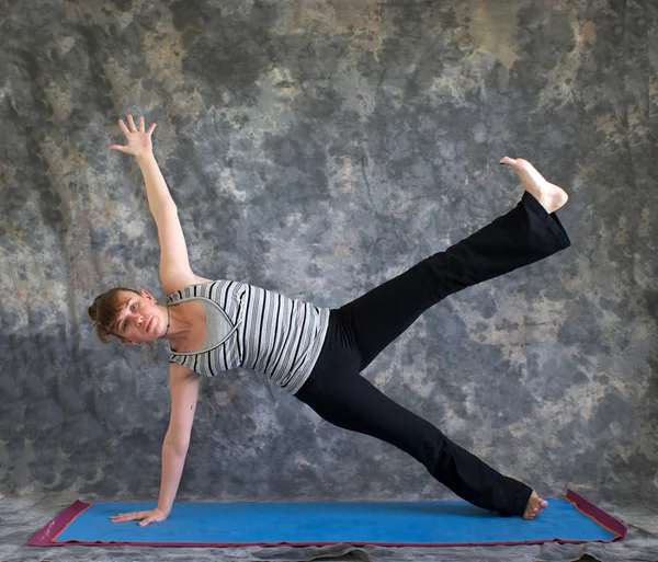 Mujer haciendo postura de Yoga Vasisthasana o tablón lateral pose variati — Foto de Stock