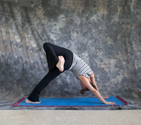 Jovem mulher fazendo postura de Yoga Eka Pada Adho Mukha Svanasana ou — Fotografia de Stock