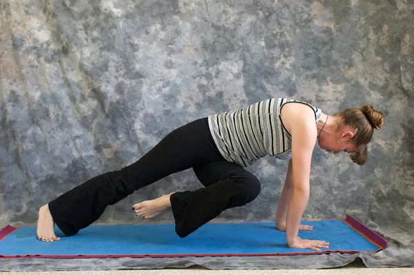 Genç kadının yapması yoga duruş yüksek tahta diz dirsek için — Stok fotoğraf
