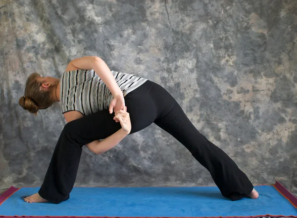 Mulher fazendo postura de Yoga amarrado postura de ângulo lateral estendido de beh — Fotografia de Stock