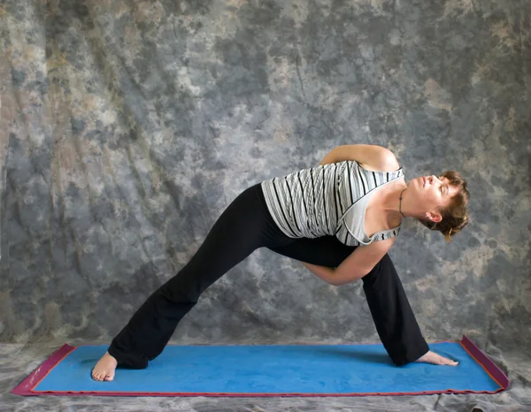 Jovem mulher fazendo postura de Yoga ligado postura de ângulo lateral estendido — Fotografia de Stock