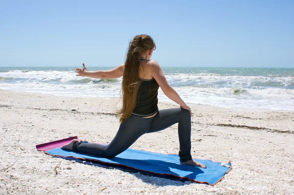 Junge Frau macht Yoga-Übungen am Strand gedreht niedrigen Ausfallschritt oder als — Stockfoto