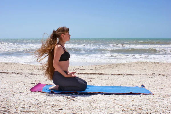 Kobieta robi ćwiczenia jogi na plaży w pozie virasana lub bohatera — Zdjęcie stockowe