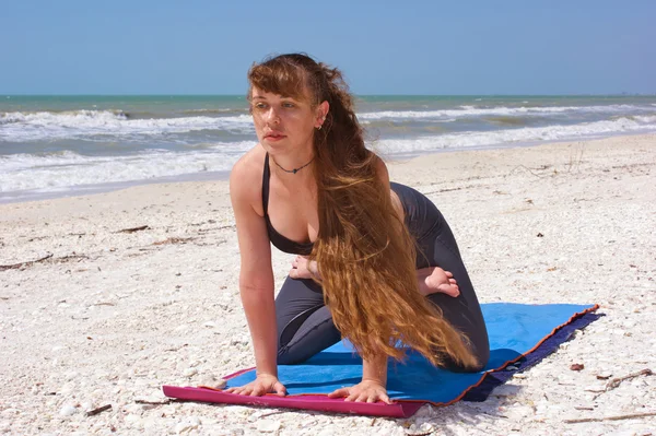 Kvinnan gör yoga övning på stranden knäfalla lotus pose — Stockfoto