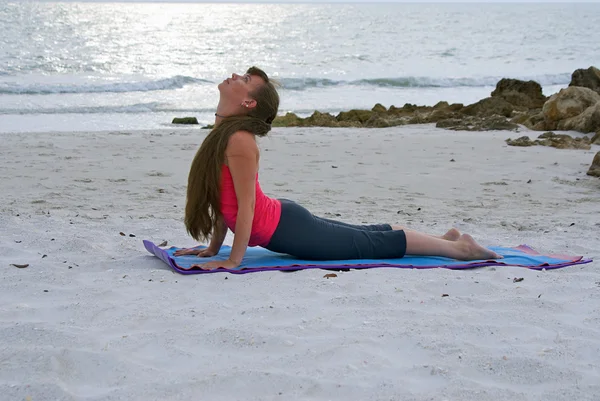 Vrouw doen yoga oefening opwaartse gerichte hond vormen op strand van zon — Stockfoto