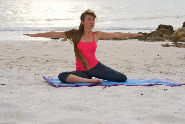 Kobieta robi joga ćwiczenia w pozycji siedzącej wojownik 2 poza na plaży o zachodzie słońca — Zdjęcie stockowe