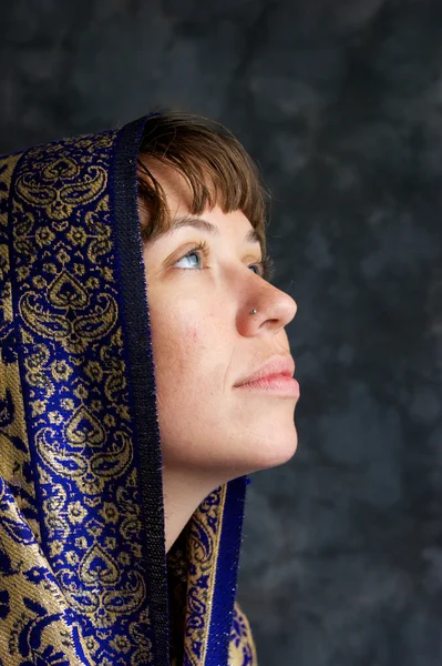 Vacker kvinna med sjal på huvudet tittar som om be — Stockfoto