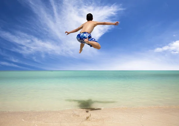 Heureux jeune homme sautant sur la plage — Photo