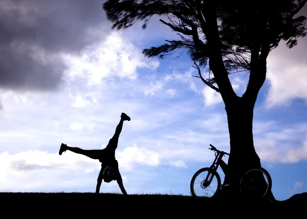 Die Silhouette eines Mountainbikers mit Handstand auf dem Hügel — Stockfoto