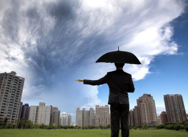 Businessman in dark suites with umbrella and watching storm clipart