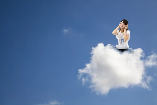 Woman listen to music and sitting on the cloud — Stock Photo, Image