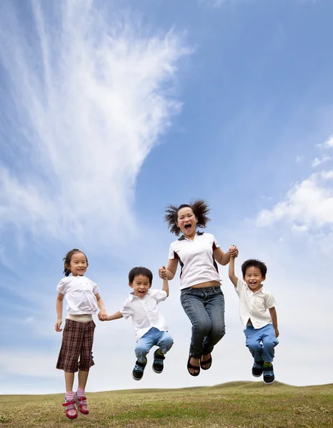 Feliz asiático família jumping no o grama campo — Fotografia de Stock