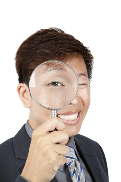 Asian businessman holding magnifier over his eye — Stock Photo, Image