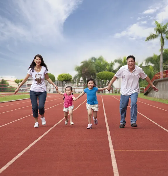 Счастливая азиатская семья бегает вместе по стадиону — стоковое фото