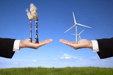 Pollution and clean energy concept. businessman holding windmills and refin