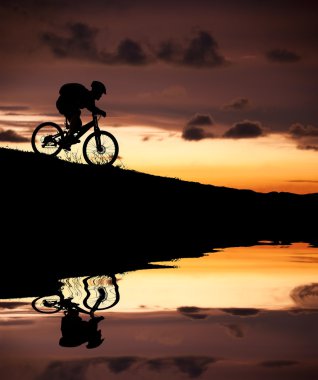 Silhouette of mountain biker with Reflection and sunset clipart