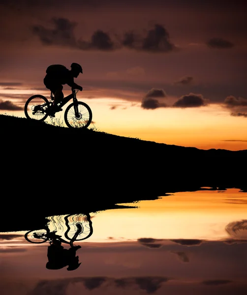 Silueta de ciclista de montaña con Reflexión y puesta de sol —  Fotos de Stock