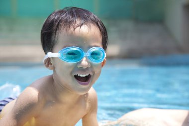 Happy asian kid in swimming pool clipart