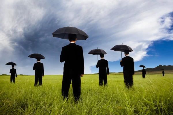 Biznesmen w czarnym garniturze gospodarstwa parasol — Zdjęcie stockowe