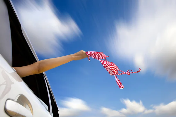 Bikini an der Hand einer Frau im schnellen Auto in die Luft halten — Stockfoto