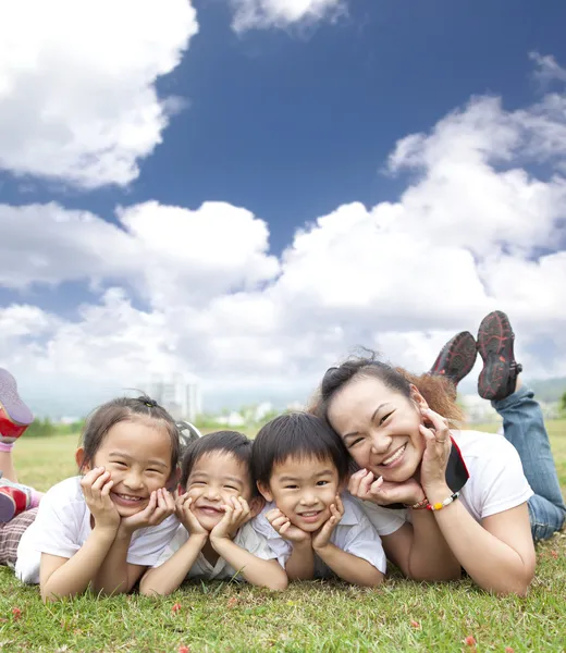 Счастливая азиатская семья на траве с облачным фоном — стоковое фото
