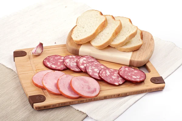 Salami slicing naast brood en knoflook — Stockfoto