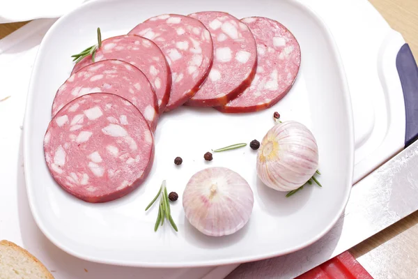 Salami slicing naast rozemarijn en knoflook — Stockfoto
