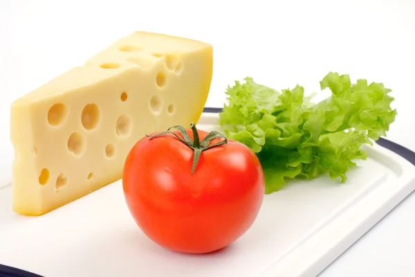 Cheese, tomato and salad sheet on a white board — Stock Photo, Image
