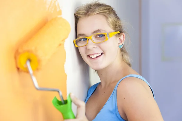 Gelukkig jonge vrouw schilderij een muur in haar kamer / kleurrijke leven — Stockfoto