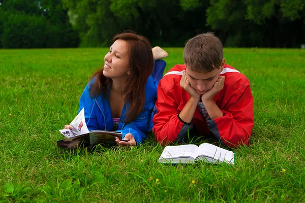 stock image Two teenagers studying outdoors on grass