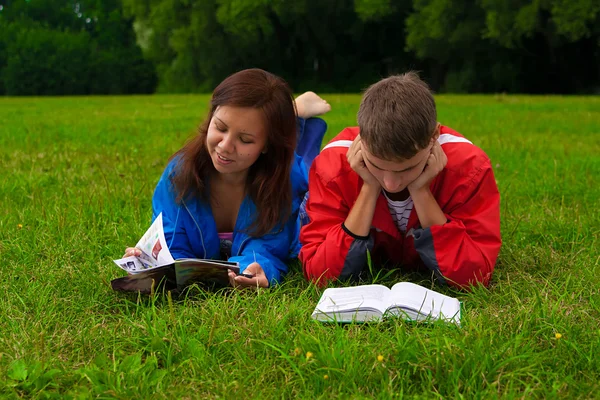 stock image Two teenagers studying outdoors on grass