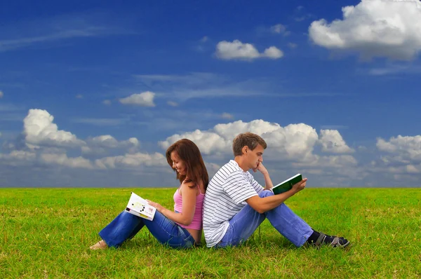 Two teenagers studying outdoors on grass Stock Photo