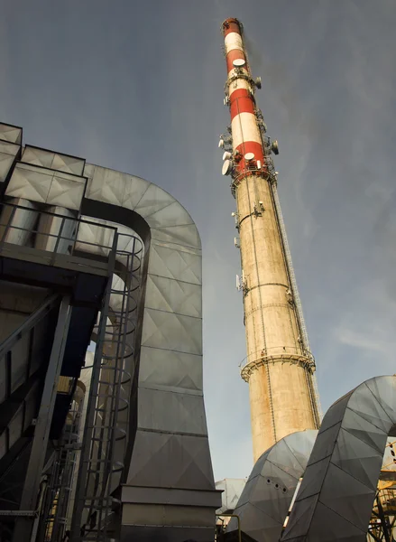 Een hoge schoorsteen met rook zichtbaar tegen de blauwe hemel — Stockfoto