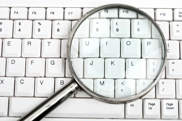 Magnifying glass on keyboard — Stock Photo, Image
