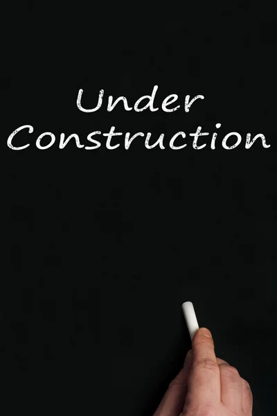Under construction on black board — Stock Photo, Image
