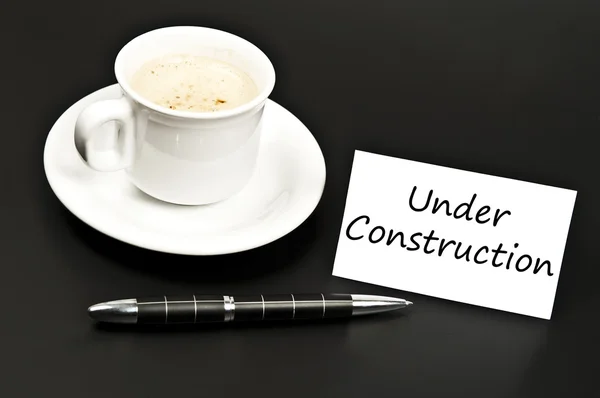Under construction message on desk with coffee — Stock Photo, Image