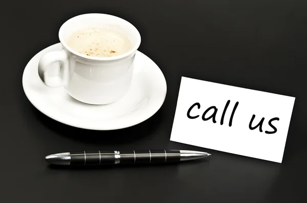Rufen Sie uns auf dem Schreibtisch mit Kaffee notiert — Stockfoto