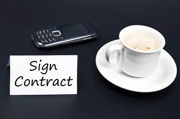 Signe le message du contrat sur le bureau avec café — Photo