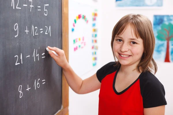 School girl writing solution on chalkboard Royalty Free Stock Images