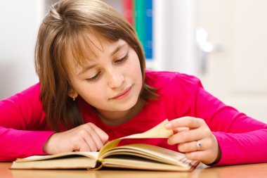 Schoolgirl reading in classroom clipart