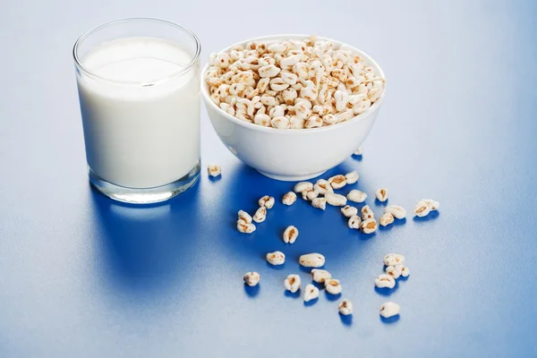 Popped wheat seeds and glass of milk — Stock Photo, Image