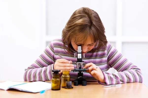 Colegiala mirando al microscopio — Foto de Stock