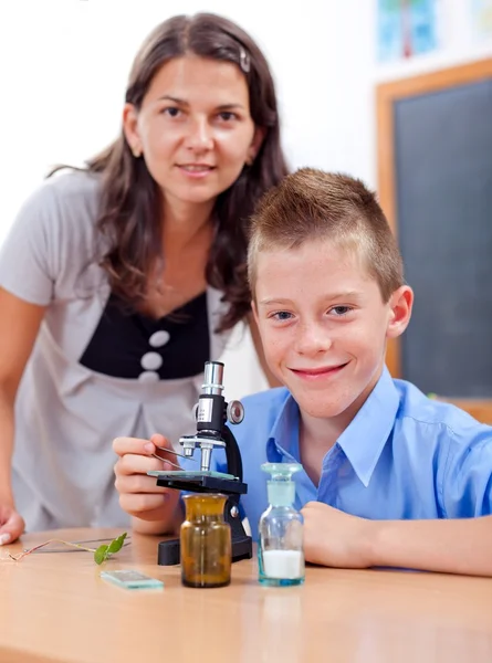 Mądry chłopak z mikroskopem i nauczyciel — Zdjęcie stockowe