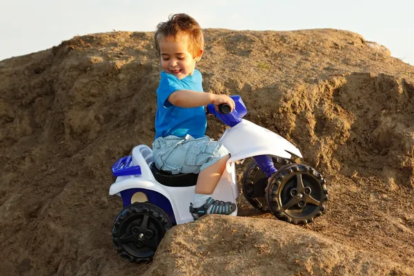 Muchacho conduciendo quad de juguete en terreno — Foto de Stock
