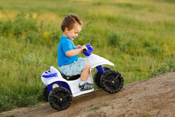 Menino dirigindo fora estrada brinquedo quad — Fotografia de Stock