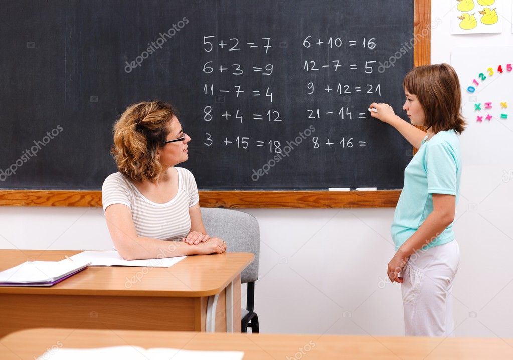Schoolgirl solving math equations at chalkboard