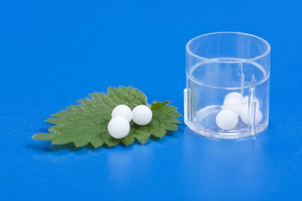 Homeopathic pills on Urtica Urens leaf — Stock Photo, Image