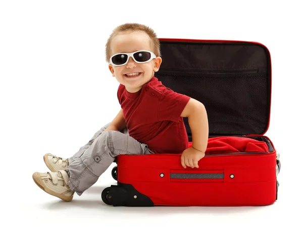 Menino brincalhão com óculos de sol, sentado na mala — Fotografia de Stock